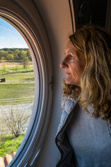 Fototapeta na wymiar A middle aged woman looking out an oval-shaped window.