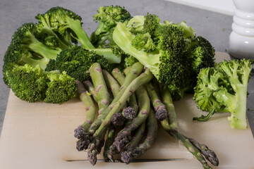 A bunch of steamed broccoli and raw asparagus. - Powered by Adobe