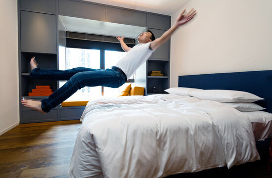Happy man jumping to the bed