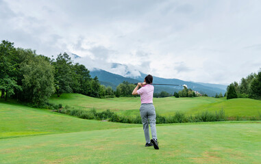 Woman golf player swinging golf club