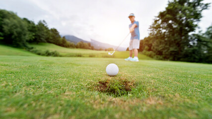 Boy putting golf ball on the hole