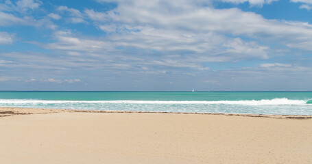 empty summer beach with yacht on horizon