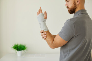 Side view of worried young man who has tendonitis or carpal tunnel syndrome wearing comfortable...