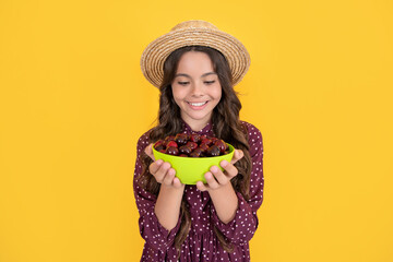 cheerful teen child hold cherry bowl on yellow background