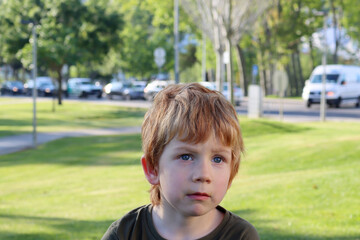 The blond boy looks into the distance with interest. A five-year-old boy with a puzzled look.