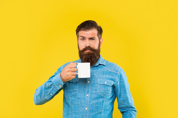 Winking guy holding tea mug yellow background