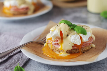 Egg benedict sandwiches - muffin with poached egg, ham and hollandaise sauce	