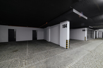 new empty large underground car park with black ceiling and cobblestones