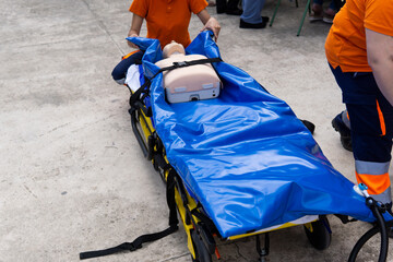 Unrecognizable ambulance nurses practising with a dummy on a stretcher