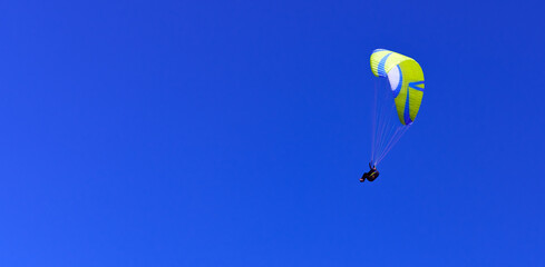 Paragliding pilot high in deep blue sky flying solo
