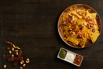 Overhead view of nachos with jalapeno served with sauces