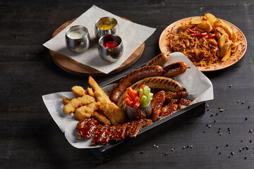 Plate with bbq pork ribbons and grilled sausages and chicken wings
