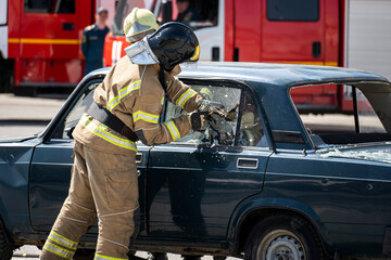 Firefighters breaking a car windscreen to help a car crash victim. Rescuers break down car that got...