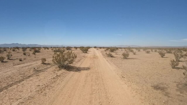 Looking back through the rear window while driving along an off-road trail in the Mojave Desert outback