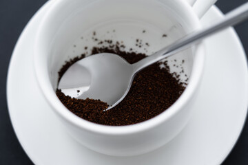close up view of ground coffee in cup with spoon.