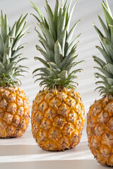 Juicy pineapple on a white background. A whole pineapple and a cut off half. Palm tree shade, creative lighting.