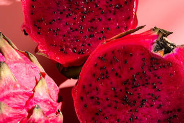 Juicy ripe pitahaya whole and scattered on a pink background. View from above. Hard light, shadow from a palm tree. Thai tropical fruits.