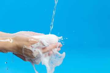 Washing hands and soap with water on blue background