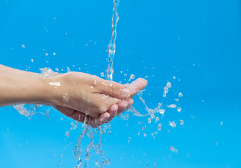 Fototapeta na wymiar Washing hands with water on blue background