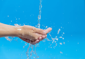Fototapeta premium Washing hands with water on blue background