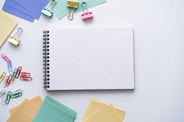 top view of blank notebook near colorful stationery on white.