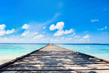 Shoreline and wooden jetty extending into the Indian Ocean. Maldives.