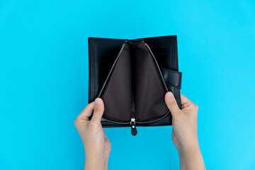 Woman hand open an empty wallet on blue background