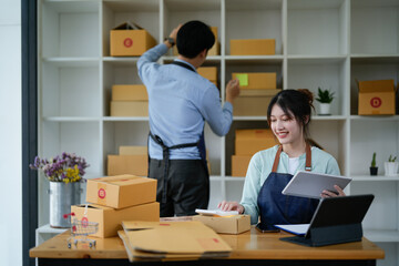 Fototapeta na wymiar startup small business owner working with tablet at workplace. freelance man and woman seller check product order, packing goods for delivery to customer. Online selling, e-commerce, shipping concept