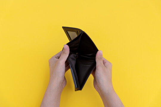 Woman hand open an empty wallet on yellow background