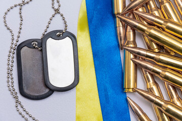 Army identification badges, ribbons of the Ukrainian flag, scattered machine-gun cartridges and live ammunition on a white background. Concept: war in Ukraine, military special operation, conscription