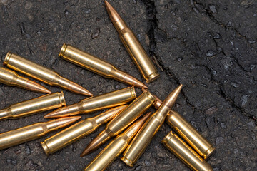A scattering of cartridges with 7.62 caliber bullets for a Kalashnikov assault rifle on the asphalt in the city, close-up, selective focusing. Concept: the war in Ukraine, urban battles, shootout.