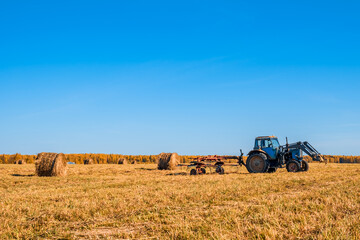 Obraz premium Tractor collecting haystacks in a field
