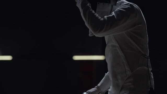 Portrait of Caucasian male fencer putting on his protective helmet, getting ready for the fight