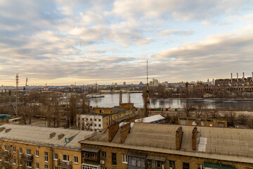Fototapeta premium Kyiv, Ukraine – February 06, 2016: A beautiful panorama of Podil region during sunset. Aerial view on residential and industrial areas. Different architectural style. Historical area, Dnipro river.