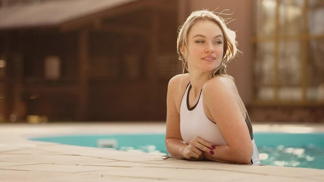 happy young woman is resting in warm thermal bath outdoor, joyful female visitor of modern spa complex and hotel
