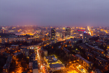 Obraz premium Ukraine, Kyiv – March 12, 2016: Aerial panoramic view on central part of Kyiv city from a roof of a high-rise building. Night life in a big city. Foggy and rainy weather. 