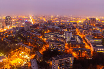 Fototapeta na wymiar Ukraine, Kyiv – March 12, 2016: Aerial panoramic view on central part of Kyiv city from a roof of a high-rise building. Night life in a big city. Foggy and rainy weather. 