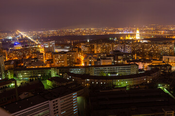 Ukraine, Kyiv – March 12, 2016: Aerial panoramic view on central part of Kyiv city from a roof of a high-rise building. Night life in a big city. Foggy and rainy weather. 