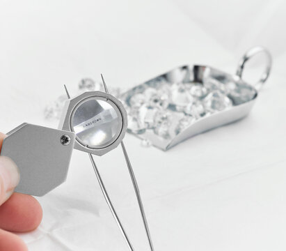 Lab Diamond Held in Tweezers Viewed in Loupe with Lab Diamond Laser Inscription on the Diamond Girdle