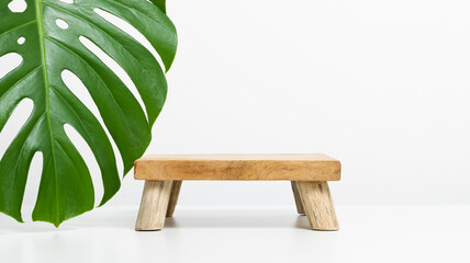 Wooden product podium with monstera leaf on white background. Blank background for product...