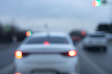 Blurred view of cars driving down the road with headlights on on a cloudy day