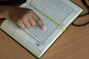 Naklejka premium Muslim Woman in mosque reading Quran On Wood Background concept of Islamic education