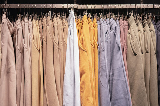 Lots of pastel-colored women's knit sweatpants hang in a row on a hanger. Clothing store