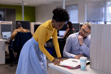 African american businesswoman discussing over document with caucasian businessman at workplace