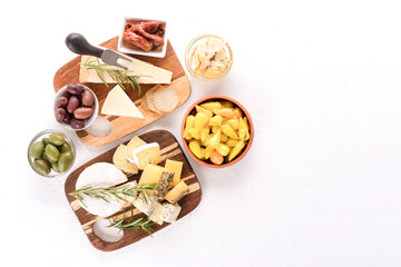 Selection of cheeses with variety of antipasti on wooden boards - olives, baby and sun dried...