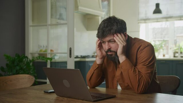 Stressed bu sinessman recieving bad news on his laptop indoors