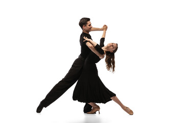 Two young graceful dancers wearing black stage outfits dancing ballroom dance isolated on white...