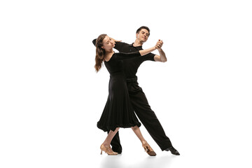 Two young graceful dancers wearing black stage outfits dancing ballroom dance isolated on white background. Concept of art, beauty, music, style.