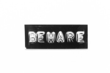 Black color banner that have embossed letter with word beware on white paper background