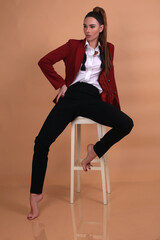 Portrait of a fashionista in the studio dressed in an elegant jacket and trousers, barefoot